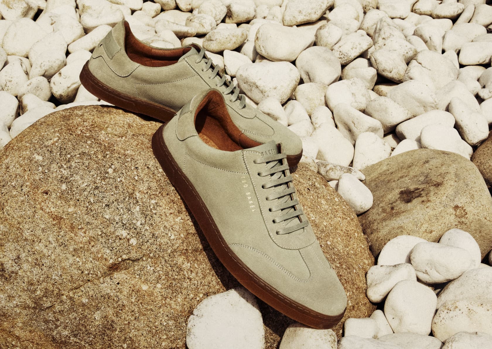 Men's grey suede trainers on a rock