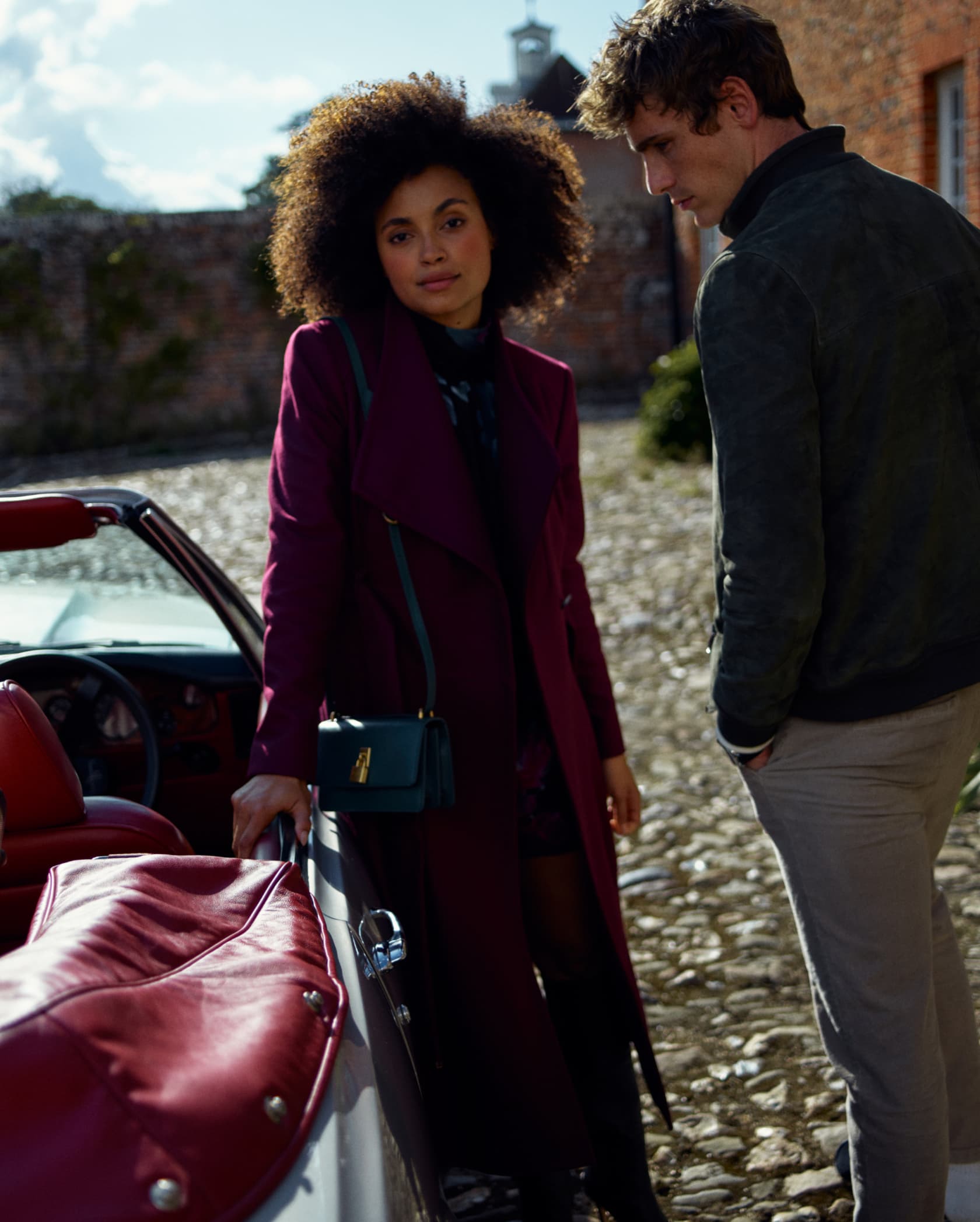 Woman and man in Ted Baker outerwear, woman in a red burgundy coat, man in a green khaki jacket