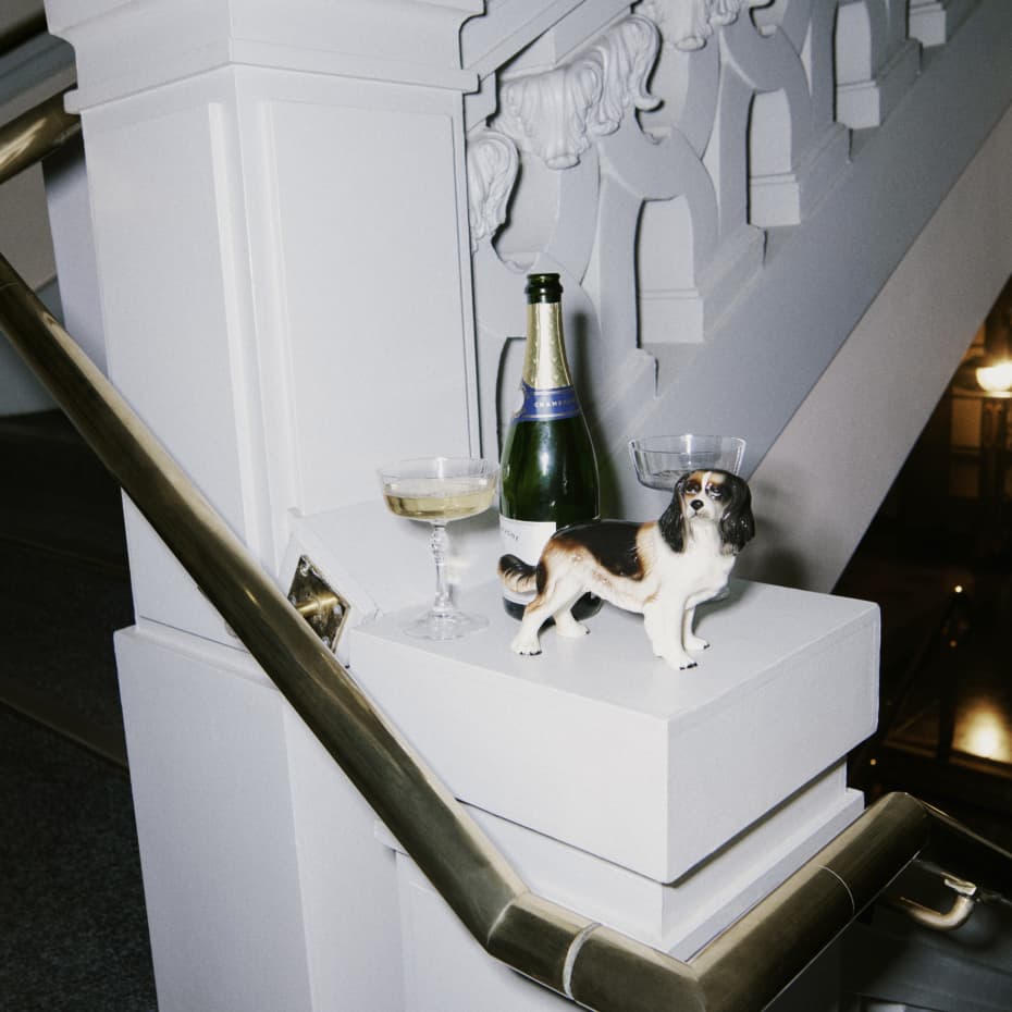 Staircase with a gold bannister featuring a small dog statue and champagne bottle and two glasses