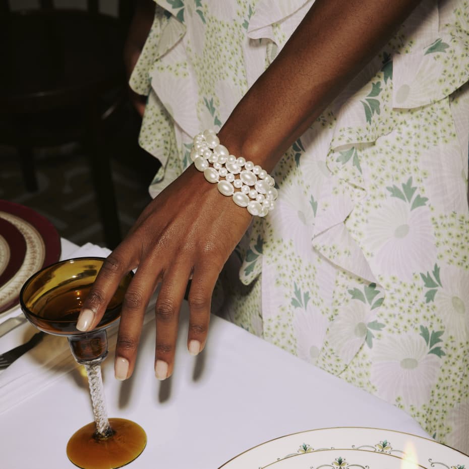 Woman in a floral print dress wearing a pearl bracelet