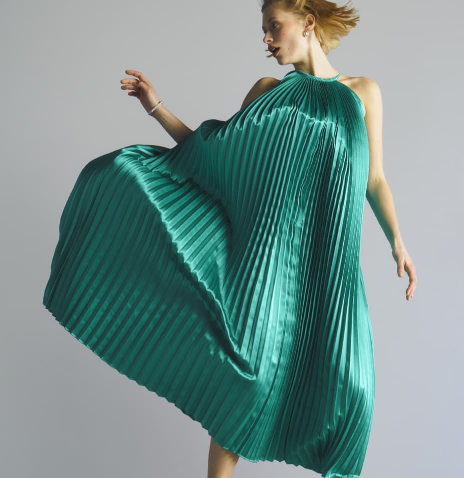 Woman jumping in a teal pleated dress