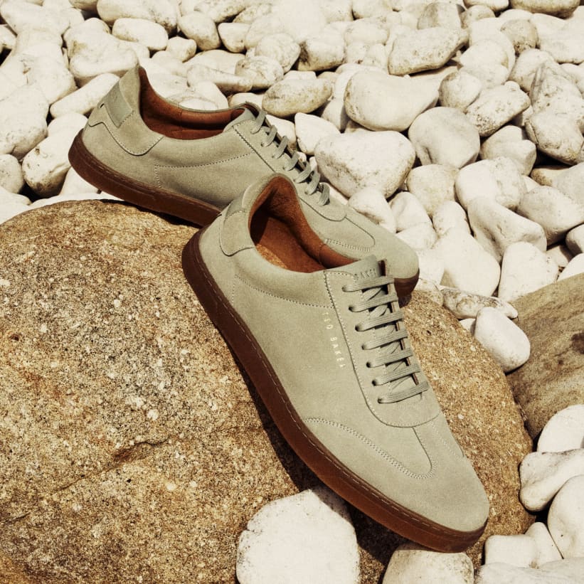 Men's trainers on a brown rock, with small white rocks behind