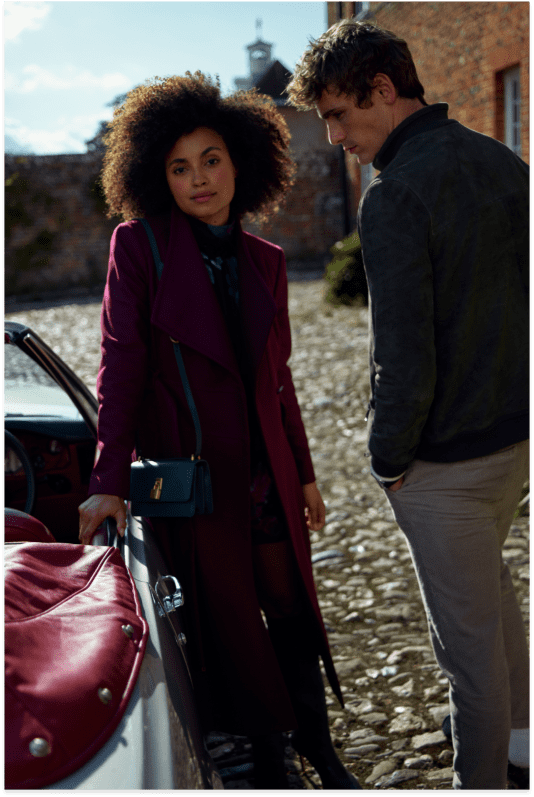 Woman in a long burgundy wool coat and man in a green fleece jacket on the right