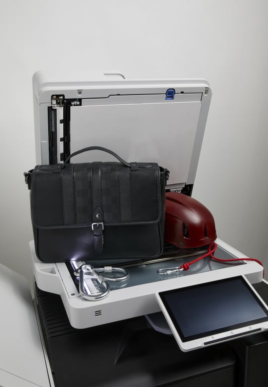 Men's black workbag on top of printer with burgundy helmet on the side and climbing rope