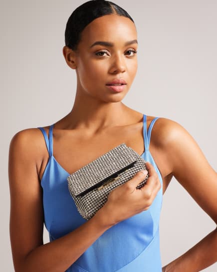 Woman in a blue dress holding a silver crystal mini cross body bag