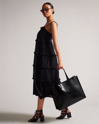 Woman in a black dress carrying black tote bag