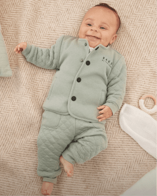 Baby in a blue set laid on a blanket