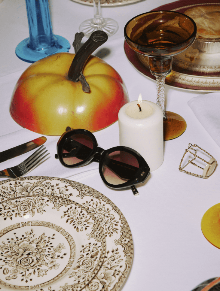 Woman's sunglasses on a table next to a candle