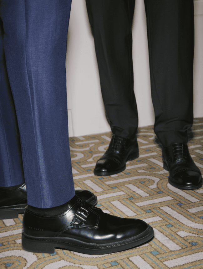 Men's suit trouser legs wearing black leather shoes