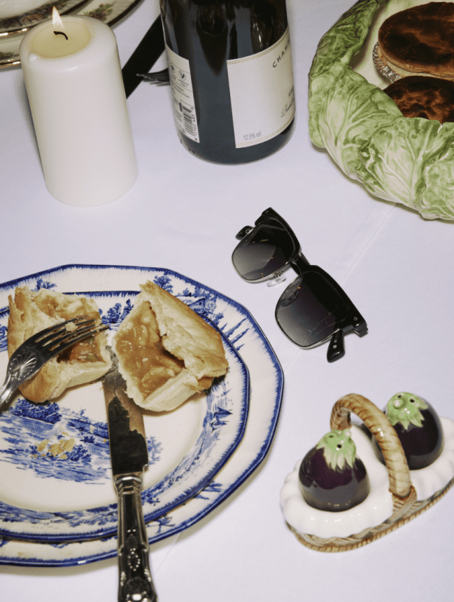 Men's sunglasses on a table next to a a dinner plate