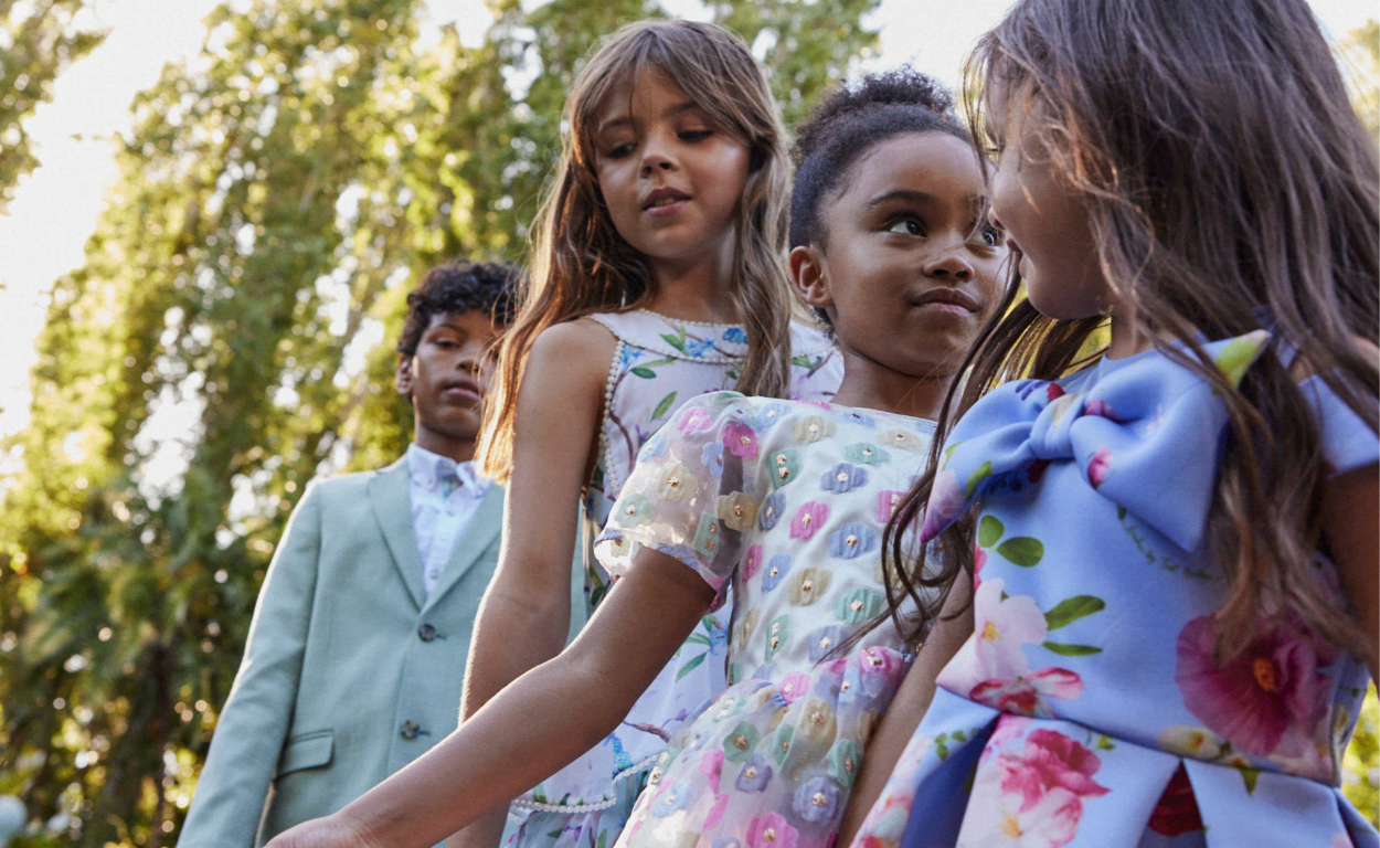 Three girls occasion dresses in the front and a boy in back green suit